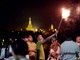 Rapaz solta fogos em Yangon com o dourado Pagode Shwedagon ao fundo
