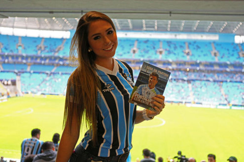 Carol Portaluppi posa antes do jogo, com foto do pai. A estreia de Renato Gaúcho na Arena Grêmio não ficou apenas marcada pela
 vitória por 2 a 1 sobre o Botafogo. O treinador levou sua filha, Carol 
Portaluppi, para acompanhar a partida contra os cariocas. Convidada 
especial do mandatário tricolor, Fábio Koff, Carol assistiu ao jogo do 
time de coração no camarote da presidência