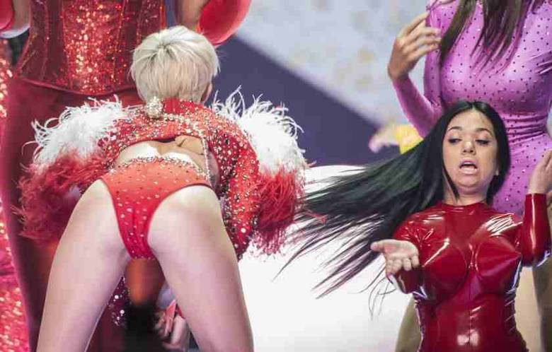 Em outro look, Miley Cyrus apareceu com um biquíni vermelho também bem cavado. Com o bumbum virado para a plateia, ela empinou o popozão, parecendo uma funkeira brasileira Em outro look, Miley Cyrus apareceu com um biquíni vermelho também bem cavado. Com o bumbum virado para a plateia, ela empinou o popozão, parecendo uma funkeira brasileira