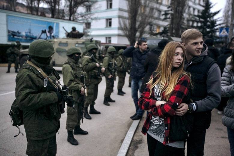 Casal fica ao lado de militares armados fora de posto na fronteira da Criméia. Neste sábado (1º), a Ucrânia acusou a Rússia de enviar milhares de soldados para a região e colocar seus militares em estado de alerta na península do Mar NegroVeja todas as notícias de Internacional