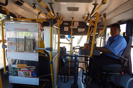 Cobrador monta estante para os livros diariamente no ônibus em que trabalha