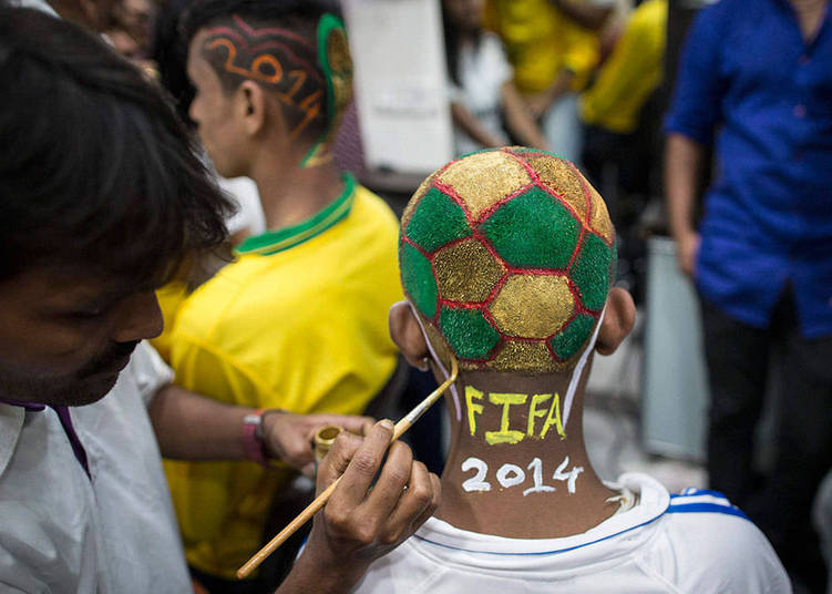 Um cabeleireiro faz cortes e pinturas de cabelo especiais durante um evento em homenagem à Copa em Mumbai, na Índia. Muitos dos homens escolheram pintar seus cabelos com as cores brasileiras