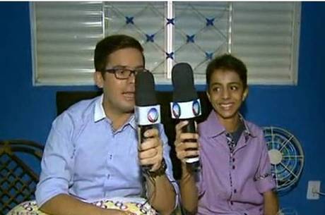 Eduardo mostra réplica do microfone, que ele mesmo fez, ao lado do repórter Bruno José