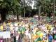 A maioria das pessoas está vestida com camisetas verde e amarelas em alusão à bandeira do Brasil, com apitos e panelas. Há várias crianças, idosos e famílias em volta do coreto da praça. Leia Mais