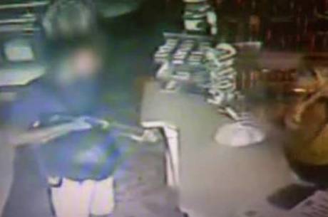 Imagem mostra o adolescente com arma apontada para atendente de caixa de uma padaria