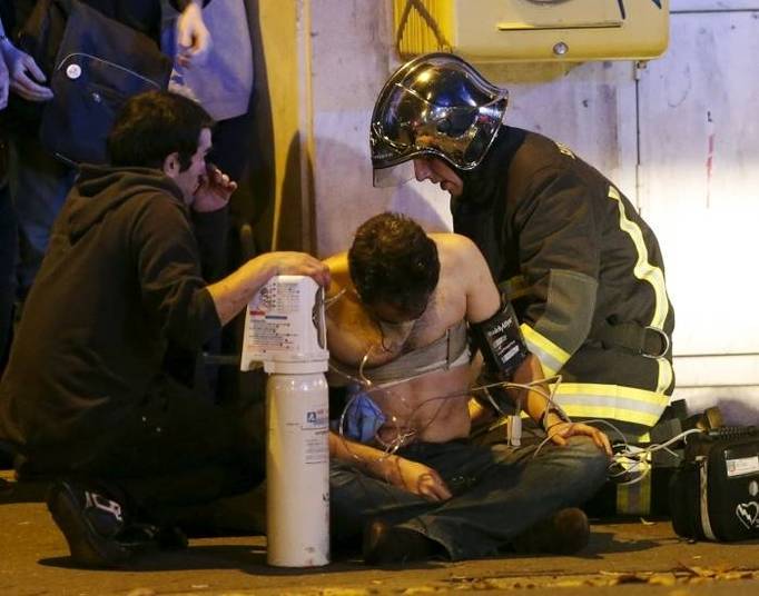 Ataques simultâneos em Paris nesta sexta-feira (13) deixaram pelo menos 129 mortos e 352 feridos, 99 deles em estado grave. Por mais de uma hora, centenas de pessoas foram feitas reféns por terroristas na casa de espetáculos Le Bataclán, onde três homens abriram fogo e mataram ao menos cem vítimas. Na foto, um ferido recebe atendimento do lado de fora da casa de shows. Um local próximo ao Estádio de França, em Saint-Denis, cidade vizinha de Paris, foi alvo de explosões, possivelmente uma ação de três homens-bomba