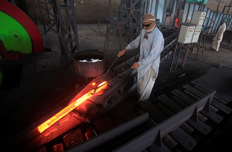 Operário retira ferro incandescente de forno em fábrica do Paquistão