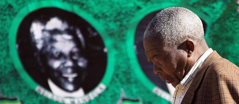 Homem passa em frente a retrato de Mandela em Soweto, na periferia de Johannesburgo