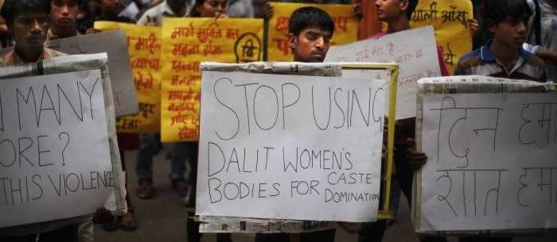 Jovem indiano segura placa que diz: "Pare de usar os corpos das mulheres dalit (casta) como castelo de dominação"
