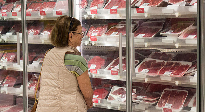 Consumidora escolhe carne em supermercado de SP. Ações da JBS e BRF recuam nesta segunda