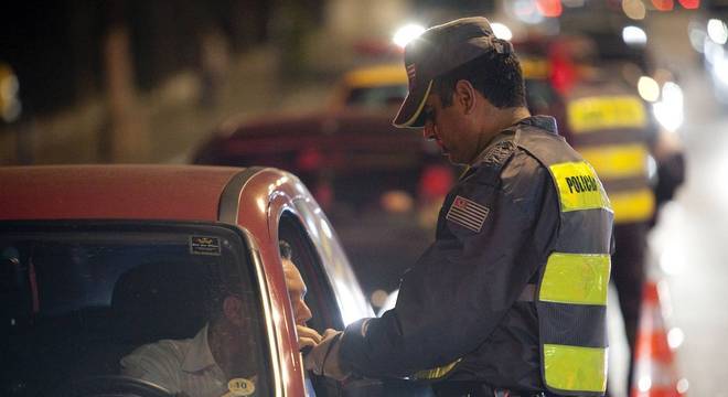 Homem fazendo o exame da bafômetro em parada policial 