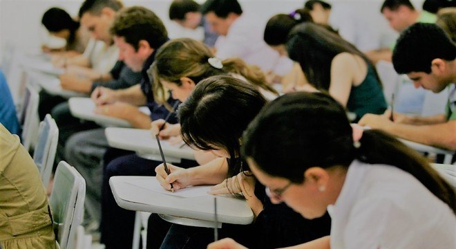 Sala de aula com candidatos fazendo uma prova de concurso público