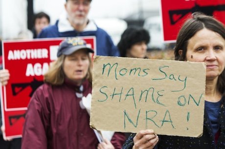 Mulher segura cartaz em que lê-se 'Mães dizem — que vergonha, NRA', em protesto contra a organização