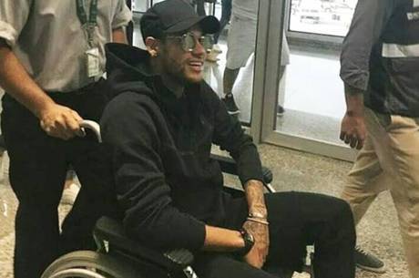 Neymar, do PSG, desembarca em cadeira de rodas no Rio