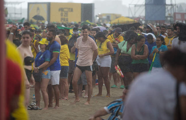 A chuva caía e o torcedor brasileiro não tirava o pé da areia. 