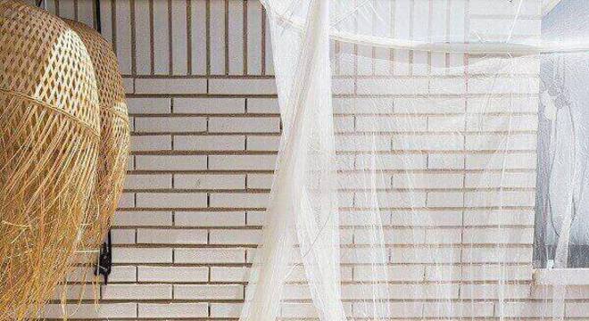 A leveza do branco se harmoniza com as almofadas coloridas da varanda boho