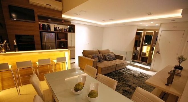 A mesa retangular branca da sala de jantar serve para dividir ambientes