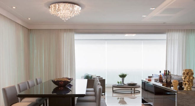 A mesa retangular de cor neutra se harmoniza com o tapete do ambiente