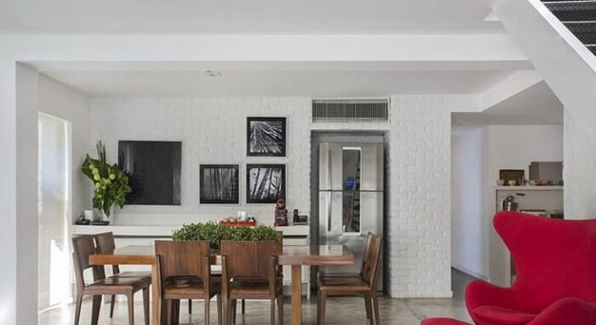 A mesa retangular de madeira se harmoniza com o piso em cimento queimado