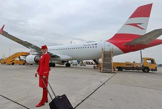 A nova foto mostra Gloria vestida com seu uniforme vermelho da Austrian Airlines, com uma mala elegante substituindo o antigo Ursinho Pooh. Ao fundo, um A320 substitui o A340 original, estacionado no aeroporto de Viena.