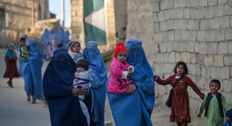 Mulheres e crianças afegãs caminham em uma rua na cidade de Ghazni