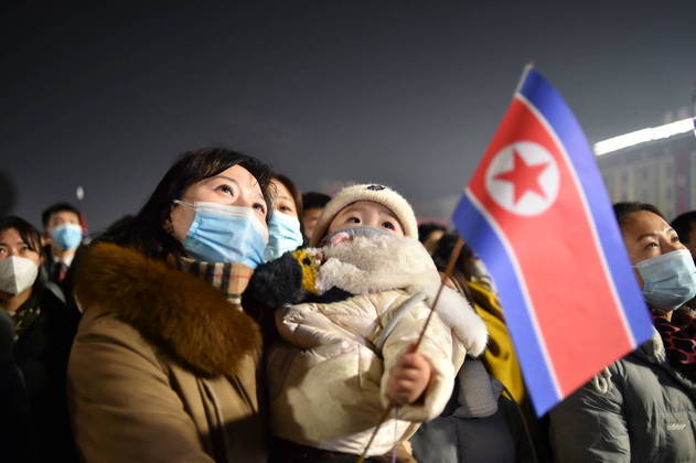 Para completar, os bebês também participaram da festa em Pyongyang. Na imagem, mãe e filho usam máscara para se proteger da Covid-19