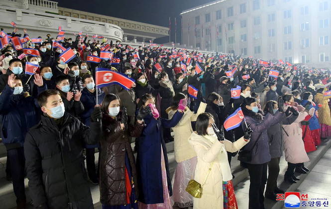 No sábado (31) à noite, como mostra esta foto da Agência de Notícias Oficial da Coreia do Norte, os moradores olham para a bandeira do país, também parte das comemorações de Ano-Novo
