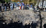 Logo após míssil atingir área em que crianças costumavam brincar, pessoas observam a cratera causada pela explosão no solo