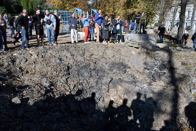 Logo após míssil atingir área em que crianças costumavam brincar, pessoas observam a cratera causada pela explosão no solo