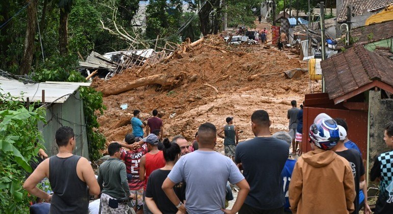 Moradores observam ruas e casas cobertas de lama após chuva torrencial