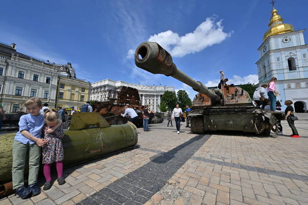 A exposição, a céu aberto, também contou com tanques russos capturados pelos ucranianos na guerra. Nesta imagem, dois meninos sentam-se em um míssil russo em Kiev