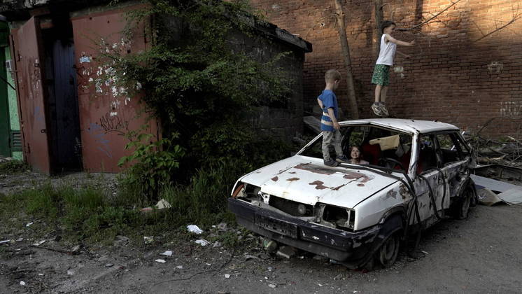 Os jovens também se divertem em cima de carros destruídos, como nesta área residencial de Mariupol, em foto feita em maio 
