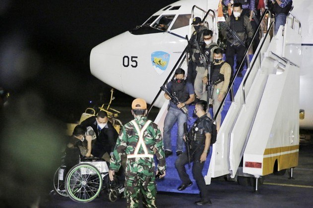 This handout picture taken and released on August 21, 2021 by Indonesia's Ministry of Foreign Affairs shows a wheelchair-bound man (bottom L) and armed personnel alighting from an Indonesian Air Force flight evacuation flight from Kabul transporting Indonesian embassy staff and their families, which includes two Afghan nationals, plus five Filipinos evacuated under the request of the Philippine government, following their arrival at Halim Airport in Jakarta. Handout / MINISTRY OF FOREIGN AFFAIRS / AFP