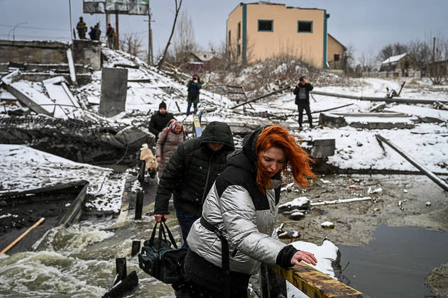 Civilians cross a river on a blown up bridge on Kyiv’s northern front on March 1, 2022. Defending capital Kyiv, the 'key priority' Ukrainian president said.
ARIS MESSINIS / AFP