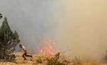 A man runs for cover as Lebanese firemen douse the flames in the forests of the Qubayyat area in northern Lebanon's remote Akkar region on July 29, 2021. A Lebanese teenager was killed as he joined volunteers battling devastating forest wildfires in northern Lebanon, where firefighters were struggling to protect homes from the blaze.
JOSEPH EID / AFP
