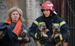 Bombeiro ajuda mulher ferida a carregar os cães depois dos múltiplos ataques a Kiev e outras cidades ucranianas 