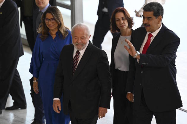 Venezuela's President Nicolas Maduro (R) waves next to Brazilian President Luiz Inacio Lula da Silva and his wife Rosangela "Janja" da Silva upon arrival at Planalto Palace in Brasilia on May 29, 2023. The President of Brazil, Luiz Inácio Lula da Silva, meets this Monday in Brasilia with his Venezuelan counterpart, Nicolás Maduro, who traveled to the Brazilian capital to participate in a "retreat" on Tuesday together with the other South American leaders.