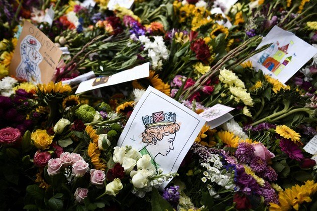 A picture of Britain's Queen Elizabeth II is seen amongst flowers placed by well-wishers outside Windsor Castle on September 18, 2022, following the death of Queen Elizabeth II on September 8. Britain was gearing up Sunday for the momentous state funeral of Queen Elizabeth II as King Charles III prepared to host world leaders and as mourners queued for the final 24 hours left to view her coffin.
STEPHANE DE SAKUTIN / AFP
