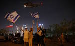 A população de Israel comemorou a soltura dos reféns nesta sexta. Na imagem, com bandeiras do país, os moradores de Petah Tikva saúdam a chegada de alguns libertos ao Centro Médico Infantil Schneider
