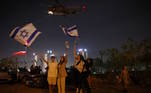 A população de Israel comemorou a soltura dos reféns nesta sexta. Na imagem, com bandeiras do país, os moradores de Petah Tikva saúdam a chegada de alguns sequestrados no Centro Médico Infantil Schneider