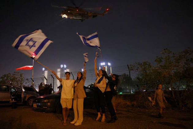 A população de Israel comemorou a soltura dos reféns nesta sexta. Na imagem, com bandeiras do país, os moradores de Petah Tikva saúdam a chegada de alguns sequestrados no Centro Médico Infantil Schneider
