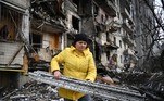 A woman clears debris at a damaged residential building at Koshytsa Street, a suburb of the Ukrainian capital Kyiv, where a military shell allegedly hit, on February 25, 2022. Russian forces reached the outskirts of Kyiv on Friday as Ukrainian President Volodymyr Zelensky said the invading troops were targeting civilians and explosions could be heard in the besieged capital. Pre-dawn blasts in Kyiv set off a second day of violence after Russian President Vladimir Putin defied