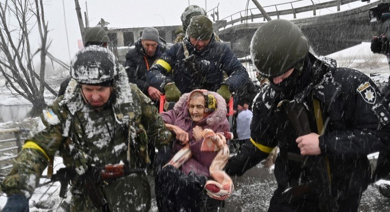 Soldados carregam idosa em fuga em Irpin, nordeste de Kiev, na Ucrânia