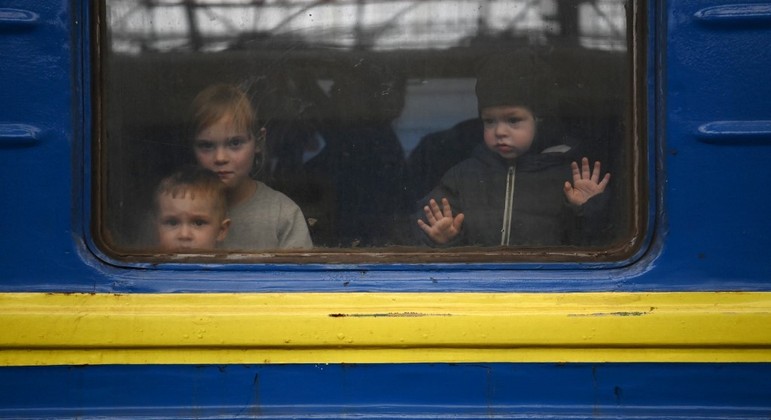 Crianças ucranianas deixam a estação de Kiev em trem que vai levá-las para a Polônia