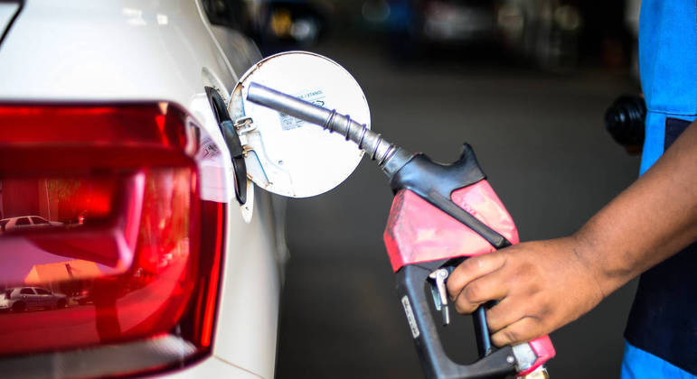 Homem abastece carro em posto de combustível