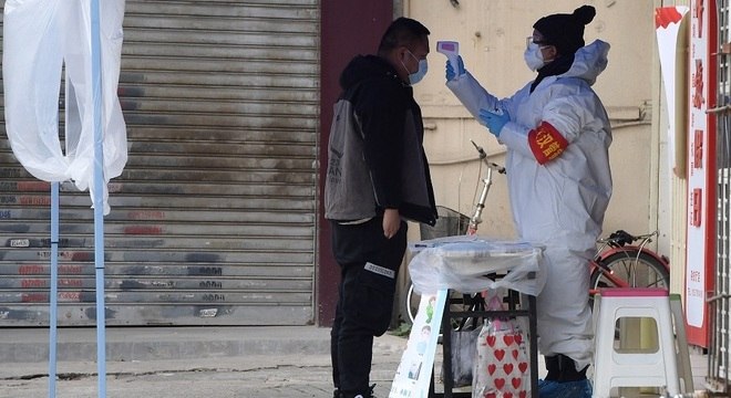 Agentes de saúde mede temperatura de passante nas ruas de Hubei