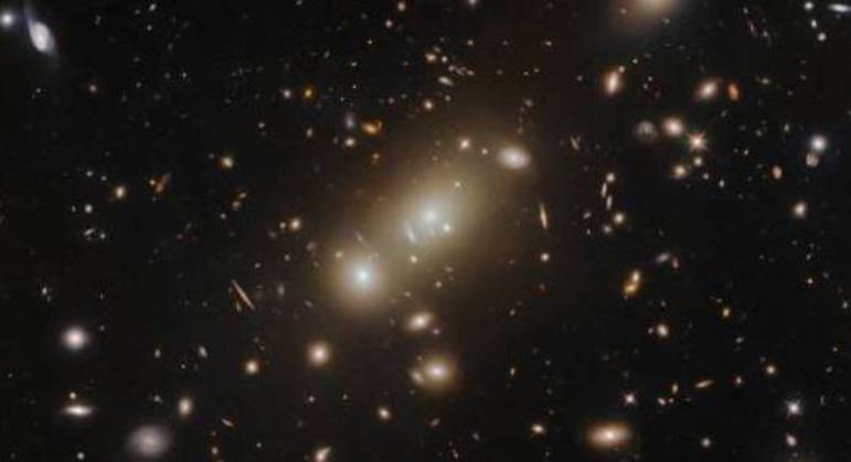 A foto do telescópio Hubble mostra o gigantesco aglomerado de galáxias 2MASX J05101744-4519179. Os cientistas afirmam que observar aglomerados como esse pode avançar nosso entendimento da evolução e interações da matéria escura e luminosa em todo universo