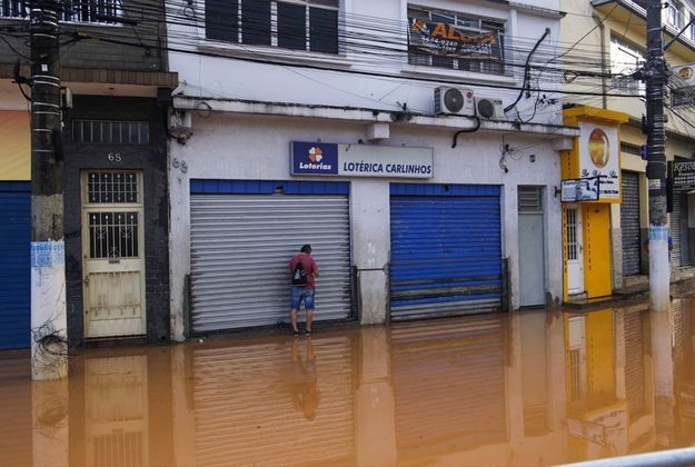 Imagens mostram moradores e comerciantes ao tentar enfrentar a enchente deixada pelo temporal. O trânsito na região também foi impactado