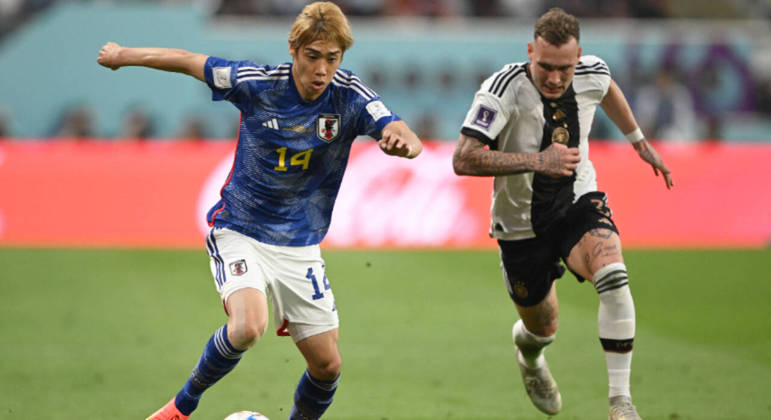 Junya Ito domina a bola e é perseguido por David Raum na partida entre Alemanha e Japão