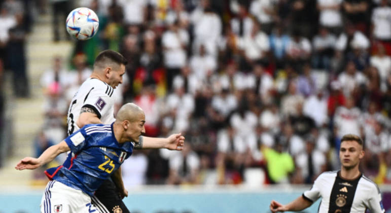 Niklas Suele e Daizen Maeda disputam a bola na partida entre Alemanha e Japão na Copa